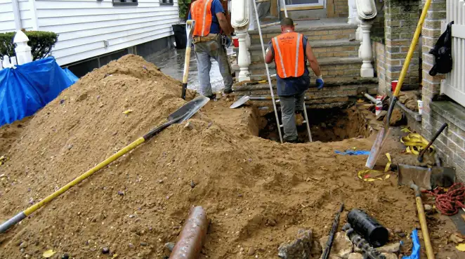 Contractors performing foundation protection and exterior drainage excavation near residential home steps in Bloomington, IN